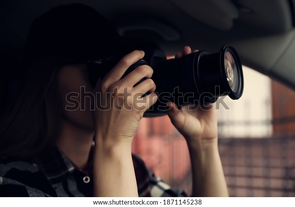 Private detective with camera spying from car, focus\
on lens