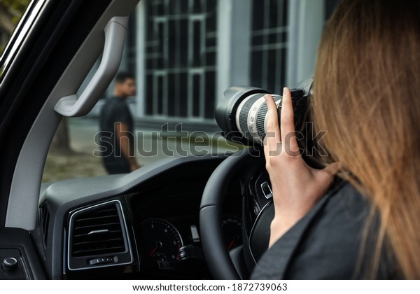 Private\
detective with camera spying from car,\
closeup