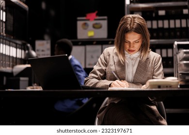 Private detective searching for new clues, working late at night at criminal case in arhive room. Police officer checking criminology report, analyzing crime scene evidence. Law enforcement concept - Powered by Shutterstock