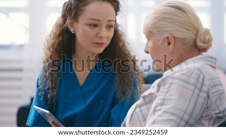 Private duty nurse teaching senior lady how to use a tablet, personal home care