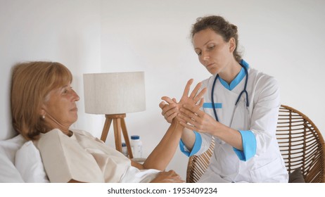 Private GP Doctor Examining Joints And Bones Of Patients Hand, Checking For Arthritis During House Call