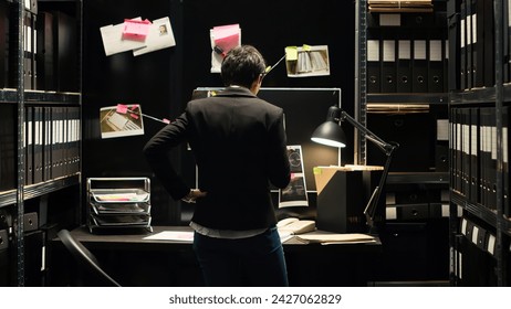 Private inspector analyzing case files, gathering intelligence to solve mistery crime. Criminologist inspecting clues, uncovering new proof to catch culprit in incident room. Handheld shot.
