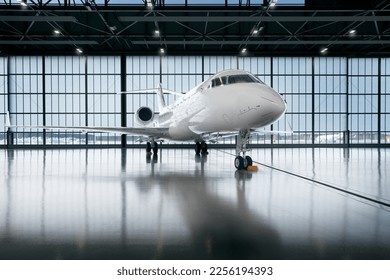 Private jet airplane at the huge white hangar waiting for maintenance and repair jobs. Expensive and luxury trip is waiting after a passengers. Business jet prepared for departure - Shutterstock ID 2256194393