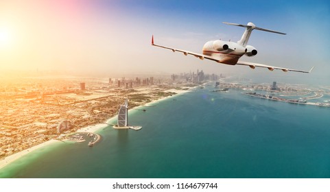 Private jet plane flying above Dubai city in beautiful sunset light. Modern and fastest mode of transportation, business life.