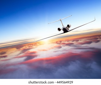 Private Jet Plane Flying Above Clouds In Beautiful Sunset. Shot From Front View