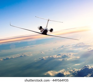 Private Jet Plane Flying Above Clouds In Beautiful Sunset. Shot From Front View