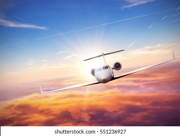 Private Jet Plane Flying Above Clouds In Beautiful Sunset. Shot From Front View. High Resolution Image