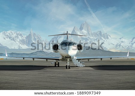 Private jet waiting to be boarded on runway with snowy mountains in the background