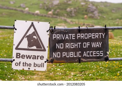 Private property sign on a metal fence in a field and beware of the bull.