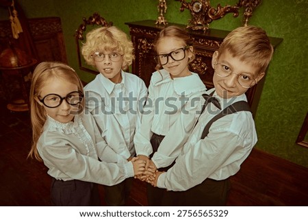 Private school students joining hands together in classic interior. Teamwork, friendship and unity concept in elite British education environment.