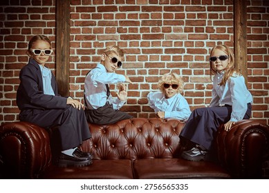 Private school students posing together on leather sofa in classic interior. Friendship, confidence and teamwork concept in elite school style.