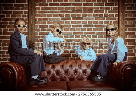 Private school students posing together on leather sofa in classic interior. Friendship, confidence and teamwork concept in elite school style.