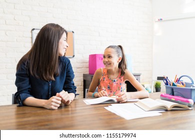 Private tutor and female student looking at each other during homeschooling at table