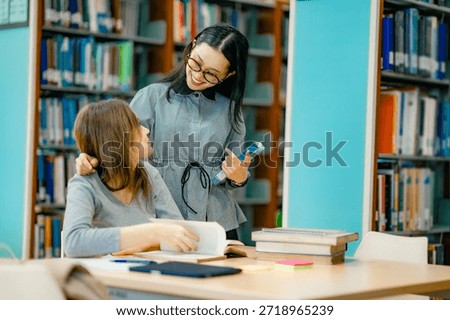 Private tutoring session inside library with tutor guiding student through reading study books showing personalized education support learning progress