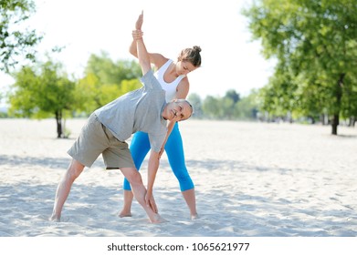 Private yoga instructor helping senior man to practice triangle yoga pose - Powered by Shutterstock