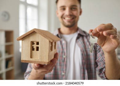 Privately Owned Home. Close Up Of Key And Small Wooden House Model In Hands Of Happy Male Real Estate Buyer. Concept Of Real Estate, Moving Home Or Renting Apartment. Selective Focus.