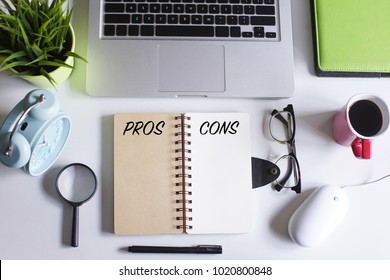 Pro and Contra concept.Laptop,magnifying glass,spectacle,pen,coffee,green plant and notebook written with text PROS and CONS on white office table.Creative office table lay out view from top. - Shutterstock ID 1020800848