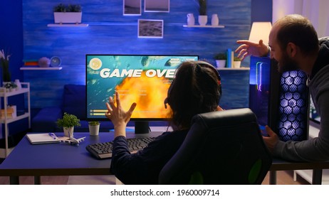 Pro Gamer Losing Space Shooter Video Game Tournament Using Professional Equipment. Game Over For Couple Of Players Use Headphones For Gaming Competition Late At Night In Living Room