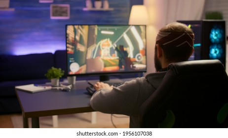 Pro Gamer Playing First Person Shooter Video Game At Gaming Home Studio Using RGB Mouse Keyboard. Virtual Online Streaming Setup With Neon Lights Cyber Performing During Game Tournament