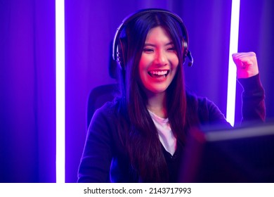 Pro Gamer. Young Pretty Asian Woman Sitting On Chair Playing Computer Pc Game Online In The Dark Room With Neon Light. Chinese Teenage Female With Headphone Professional Gamer