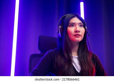 Pro Gamer. Young Pretty Asian Woman Sitting On Chair Playing Computer Pc Game Online In The Dark Room With Neon Light. Chinese Teenage Female With Headphone Professional Gamer