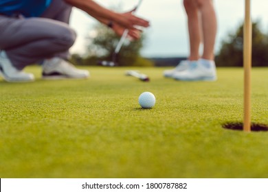 Pro On Golf Course Teaching A Woman How To Put, Close-up