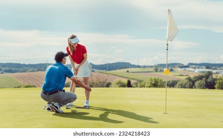 Pro on golf course teaching a woman how to put - Powered by Shutterstock