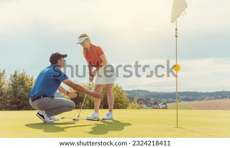 Pro on golf course teaching a woman how to put