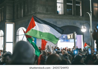 Pro - palestinian protests in Berlin. Flags of palestine waving between the people supporting palestine over israeli invasion of gaza.. Pro palestinian protests at night in european city - Powered by Shutterstock