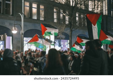 Pro - palestinian protests in Berlin. Flags of palestine waving between the people supporting palestine over israeli invasion of gaza.. Pro palestinian protests at night in european city - Powered by Shutterstock