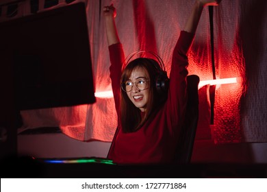 Pro player gamer winning the games young asian woman playing online shooting fps tournament ranking cyber internet at night red neon light room with gaming headset and keyboard on championship event.