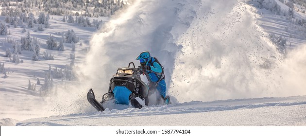 Pro snowmobiler makes a turn and lets a flurry of snow spray from under the caterpillar. sports snowmobile in the mountains. bright skidoo motorbike and suit without brands. Winter fun. panoramic view