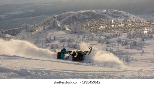 Pro snowmobiler makes a turn and lets a flurry of snow spray from under the caterpillar. sports snowmobile in the mountains. bright skidoo motorbike and suit without brands. Winter fun. panoramic view