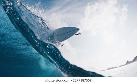 Pro surfer rides the wave. Young man surfs the ocean wave in the Maldives and aggressively turns on the lip. Splitted above and underwater view