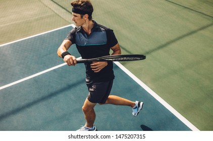 Pro Tennis Player Practicing Forehands On A Club Hard Court. Young Male Tennis Player Playing On A Club Tennis Court.