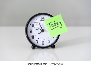 Proactive and beginning for action concept, handwriting word Today on green sticky paper over alarm clock with white wall background.