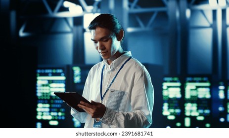 Proactive employee walking through data center electronics providing processing resources for different workloads. Organized engineer evaluating server rigs tasked with solving complex operations