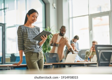 Proactive Young Woman Posing In Her Office With A Tablet