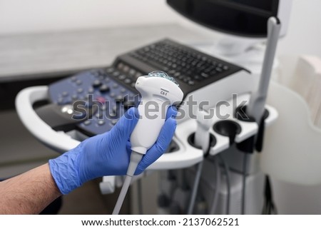Probe for ultrasound diagnostics close-up. The doctor holds in his hands a transducer with a gel for ultrasound diagnostics of internal organs. Modern ultrasonic machine. Elastography and sonography.