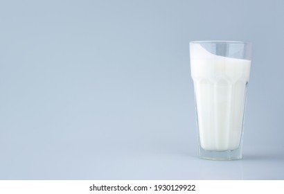 Probiotic drink, buttermilk or yogurt. Kefir in a tall faceted glass on minimalistic blue background. Bacteria Gut health,fermented products for gastrointenstinal tract.Copy space.Horizontally Banner. - Powered by Shutterstock