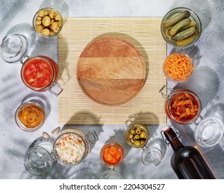 Probiotic Food. Pickled Or Fermented Products. Fermented Vegetables And Mushrooms In Glass Jars, Bottle With Home Made Beer Around Empty Wooden Plate On A Natural Mat. Home Food Preserving Or Canning