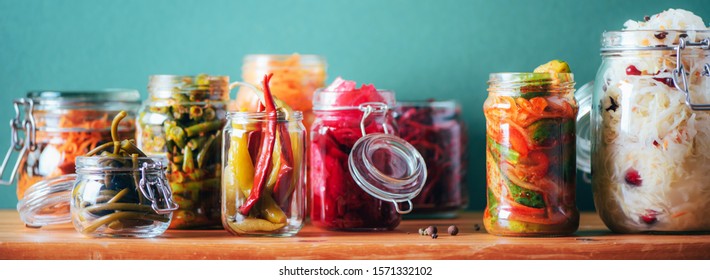 Probiotics food background. Korean carrot, kimchi, beetroot, sauerkraut, pickled cucumbers in glass jars. Winter fermented and canning food concept. Banner with copy space.