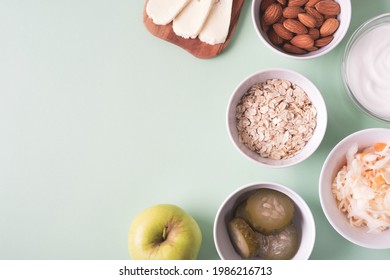 Probiotics food on light green background. Sauerkraut, pickled cucumbers, natural yogurt, cheese, almond, oatmeal, apple. Fermented foods for digestion and microbiome intestine. Top view, copy space