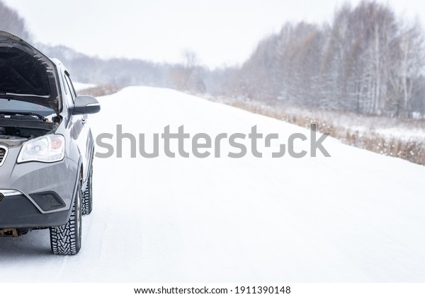 Problem with a car on a\
snow-covered road. The concept of broken cars. Panorama of a snowy\
winter road.