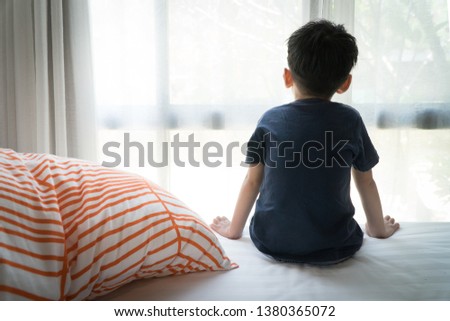 The Problem of Child Development:A little boy sitting by the bed looking through the window Absent-minded. Recognizing Developmental Delays in Children, Autism awareness, Psychological trauma.