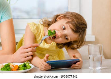 The problem is to distract the child from the phone and feed it with broccoli. Organic food and vegetables on a plate. A way to feed children - Powered by Shutterstock