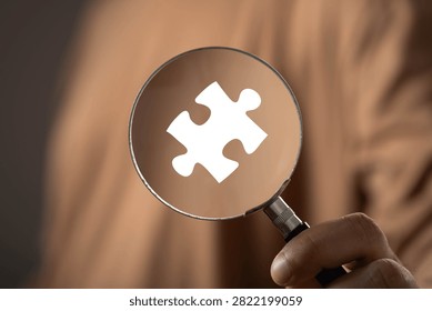 Problem solving and business analysis concept with a magnifying glass focusing on a puzzle piece. Strategic thinking, solution discovery, critical thinking, research, innovation and decision making.