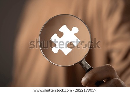 Problem solving and business analysis concept with a magnifying glass focusing on a puzzle piece. Strategic thinking, solution discovery, critical thinking, research, innovation and decision making.