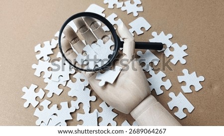 Problem Solving Concept with Hand Holding Magnifying Glass Over White Puzzle Pieces Representing Strategy, Analysis, and Search for Effective Solutions. 