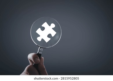 Problem solving concept with magnifying glass focusing on puzzle piece symbol, representing analysis, business solution, critical thinking, research process, strategy development and decision making.